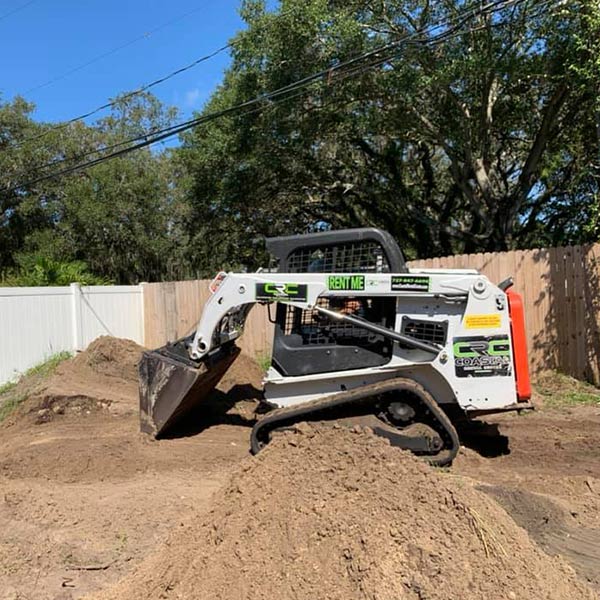 Bobcat scooping dirt into a large pile